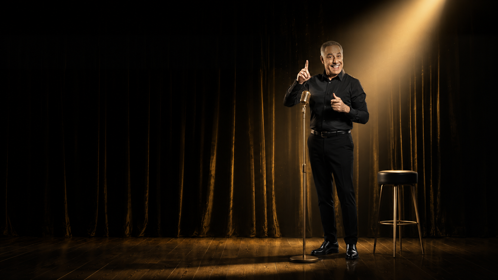 Abdelkader Secteur sur scène, avec micro, tabouret, rideau noir et lumière dorée.